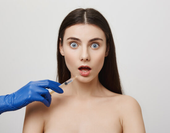 Close-up of a surprised woman receiving a botox injection.