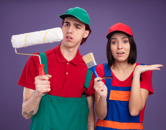 Two painters, a man and a woman, hold painting tools against a purple background.